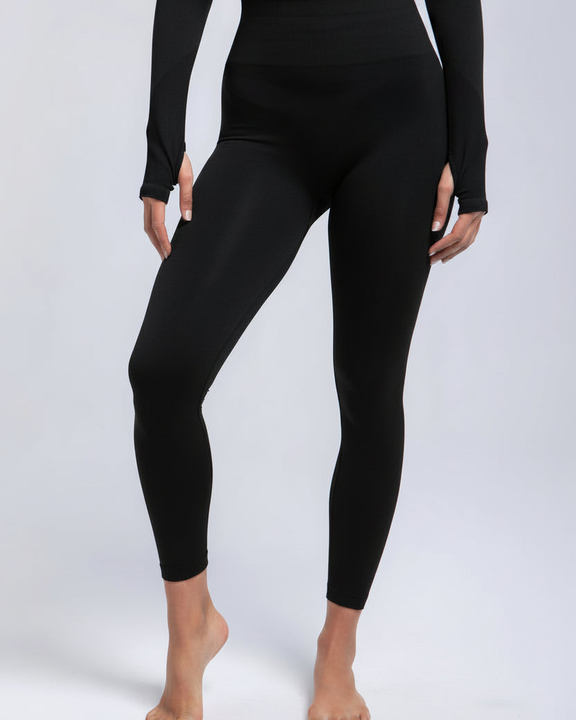 Person wearing navy leggings and long-sleeve top on a light gray background