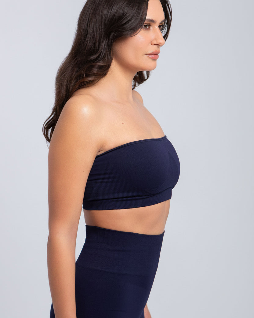 Woman wearing a navy blue strapless top and high-waisted pants against a light gray background