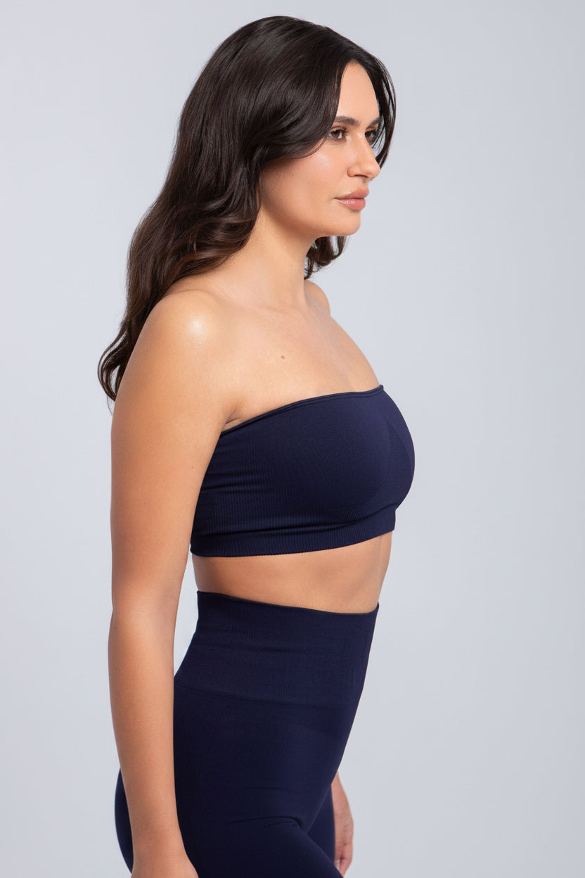 Woman wearing a navy blue strapless top and high-waisted pants against a light gray background