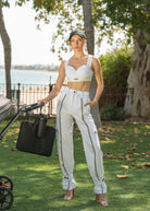 Woman in white Fierce sports bra and pants standing outdoors with a stroller.
