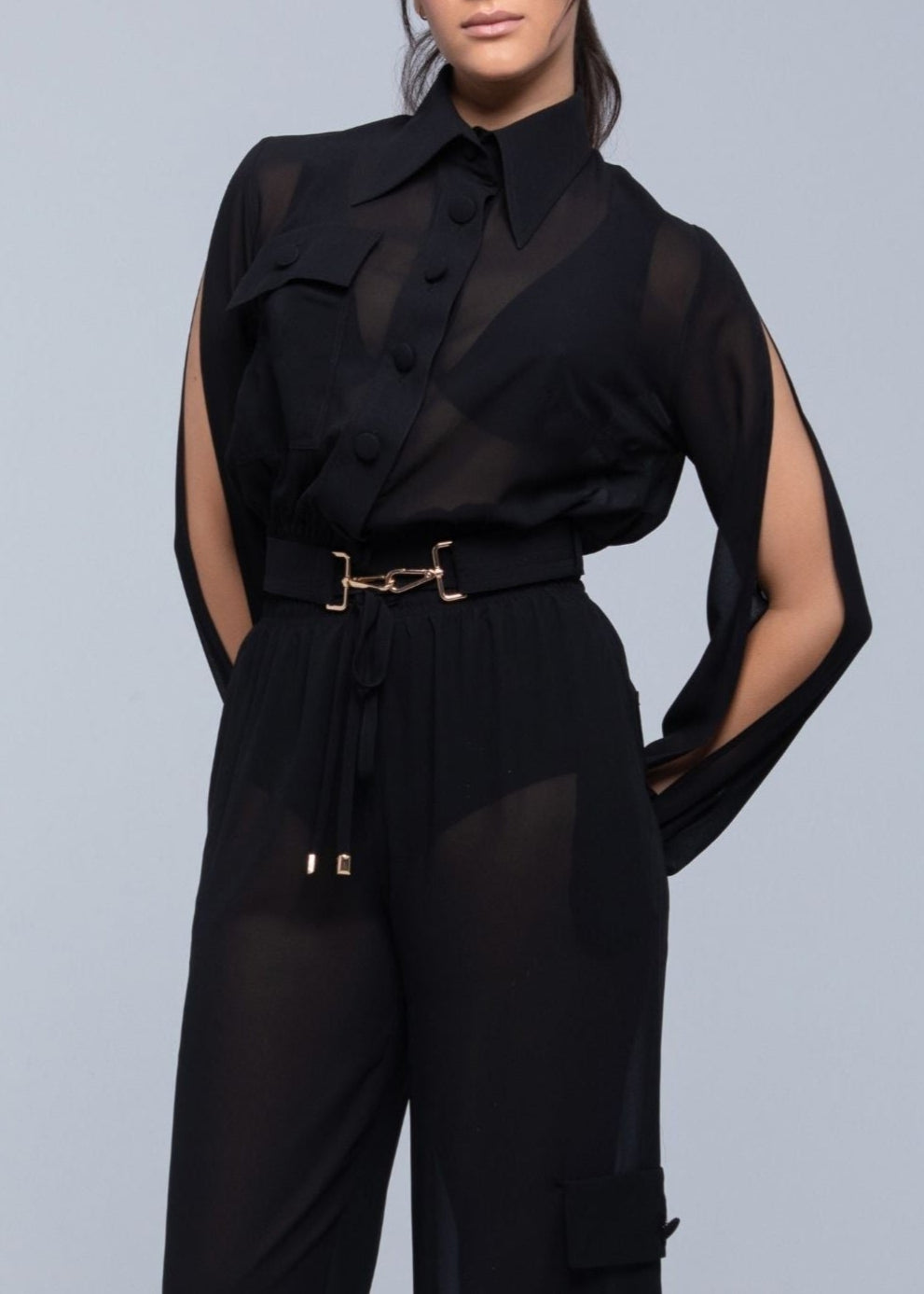 Black outfit with Fierce sheer sleeves and a belt on a gray background