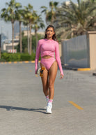 Woman in a Fierce pink outfit walking on a road with palm trees in the background