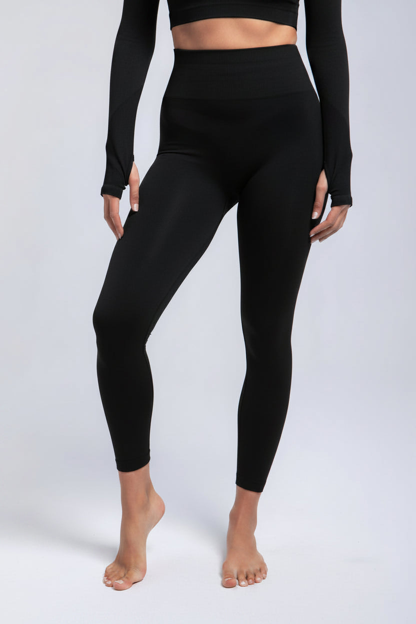 Person wearing navy leggings and long-sleeve top on a light gray background