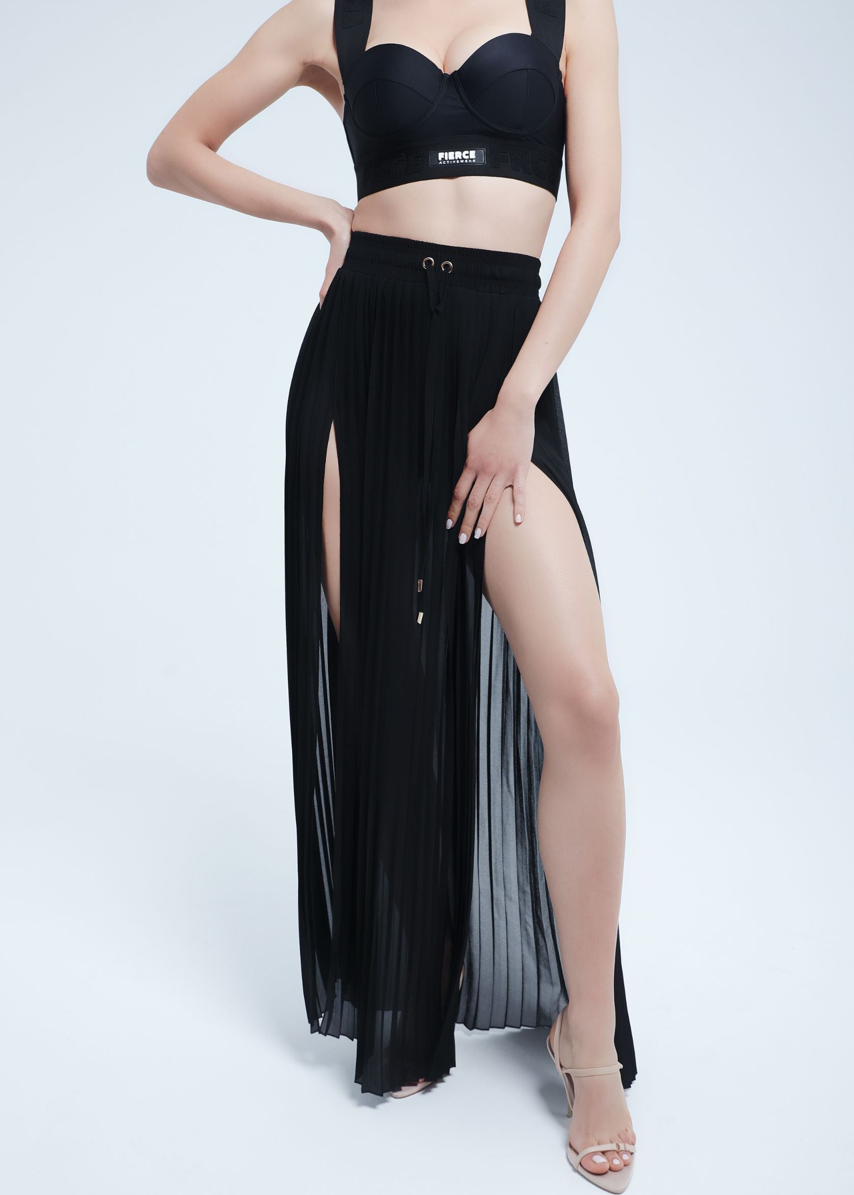 Woman wearing a Fierce black outfit with a high slit on a white background