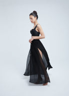 Woman wearing a Fierce black dress with a slit on a white background
