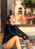 Woman in a Fierce black swimsuit sitting by a poolside with blurred background