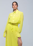 Model wearing a vibrant neon yellow Fierce long-sleeve shirt paired with a matching pleated skirt featuring a thigh-high slit and belted waist, creating a bold monochrome fashion look.