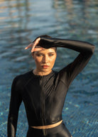 Person wearing a Fierce black wetsuit standing by water