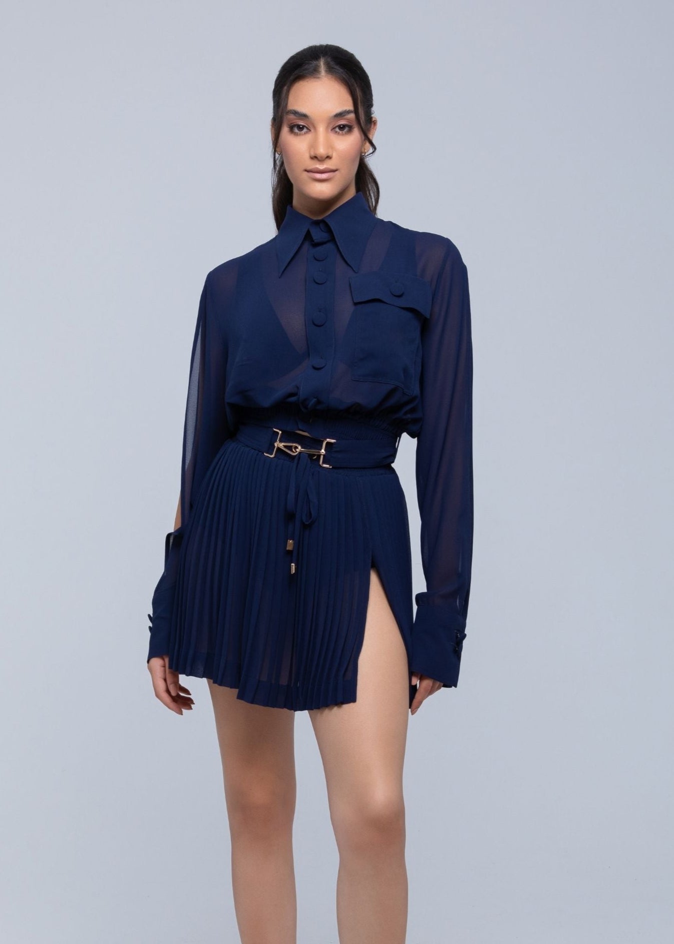 Woman wearing a navy blue Fierce outfit with a belt on a gray background
