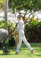 Woman in a white Fierce outfit pushing a stroller in a park