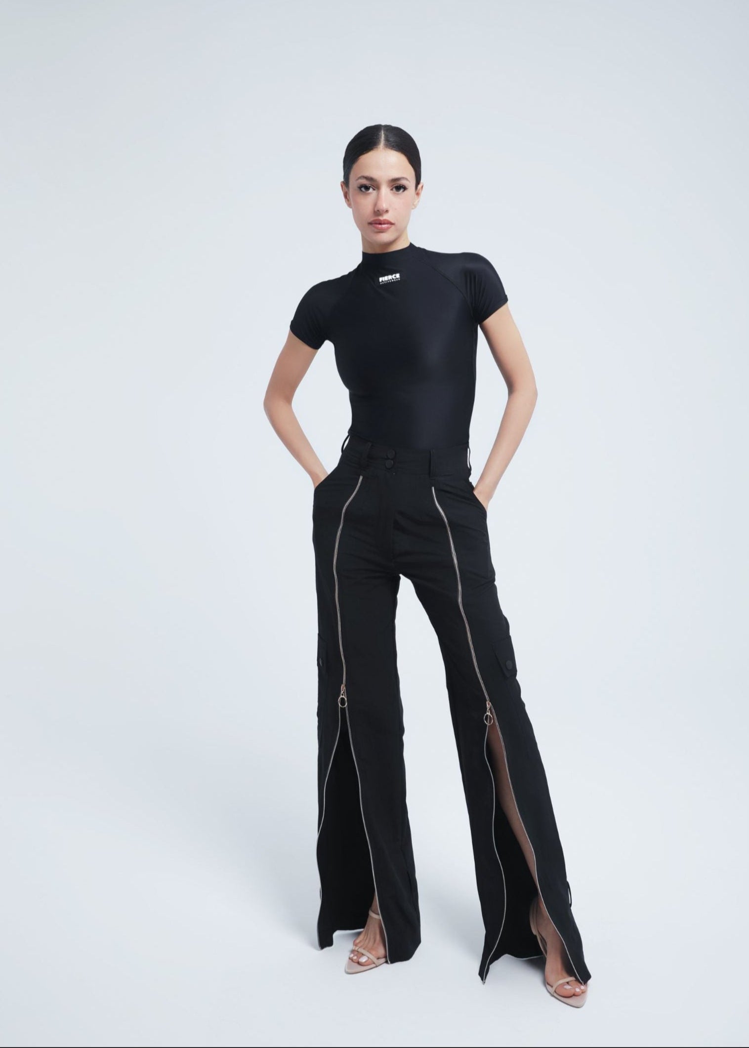 Woman wearing a Fierce black outfit with a high slit on a white background