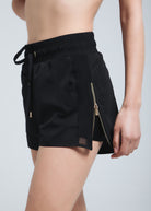 A woman is wearing white Fierce sports shorts with a drawstring waist and a matching sports bra. She is also wearing long white socks with black text on them.