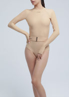 Woman wearing a beige Fierce bodysuit against a light gray background