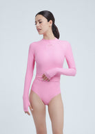 Woman wearing a pink long-sleeve Fierce swimsuit on a light gray background