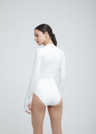 Woman wearing a white long-sleeve Fierce bodysuit on a light gray background