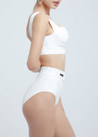 Person wearing a white Fierce sports bra and high-waisted leggings on a light gray background