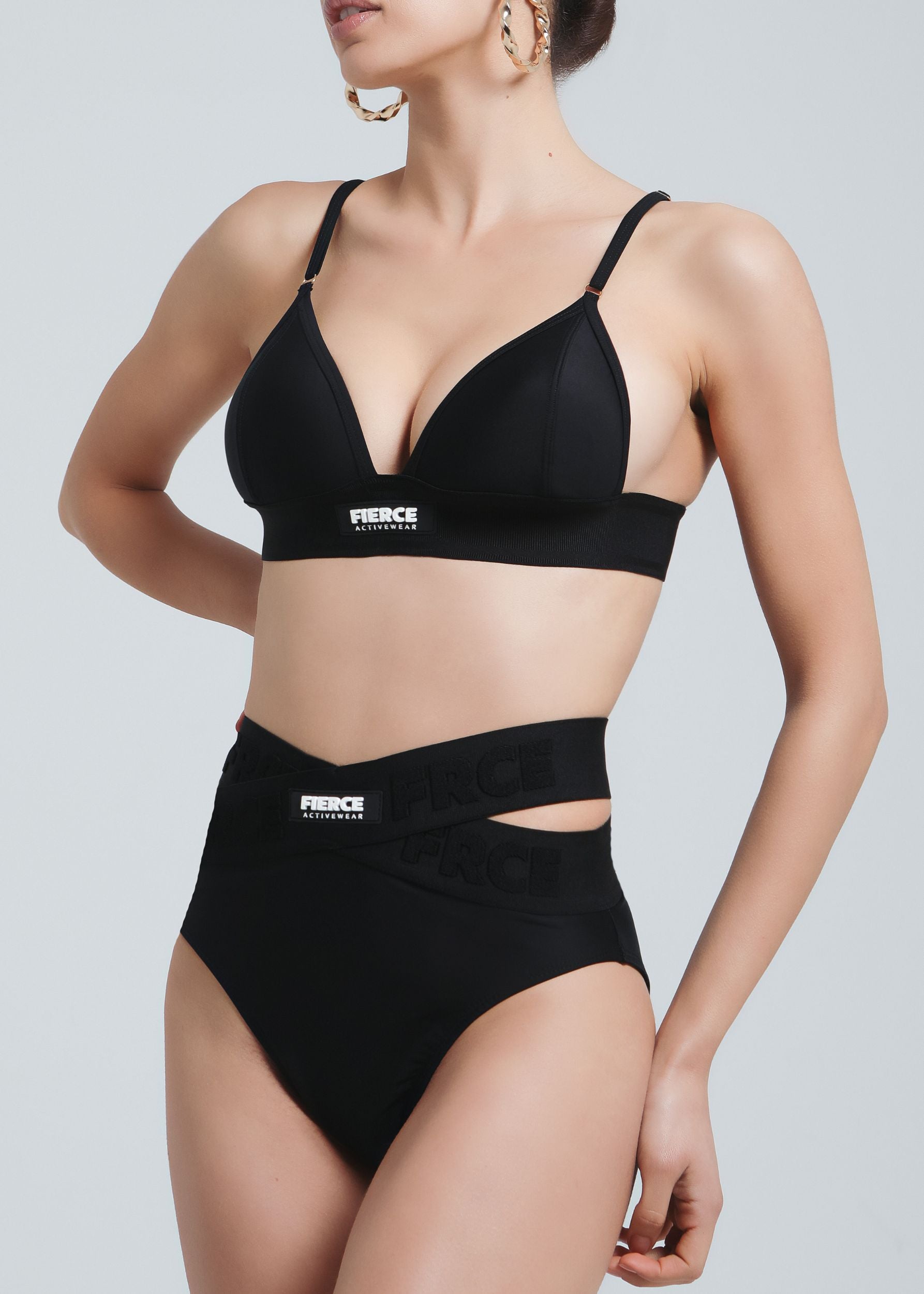 Front view of a woman wearing Fierce Activewear's black Serena triangle bikini top paired with the X-Shape high-waisted bikini bottom featuring logo details and side cut-outs