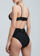 Back view of a woman wearing Fierce Activewear's black X-Shape high-waisted bikini bottom with a wide waistband, paired with a matching strappy bikini top