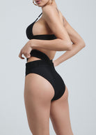 Side profile of a woman wearing Fierce Activewear's black X-Shape high-waisted bikini bottom with side cut-outs and a matching black bikini top